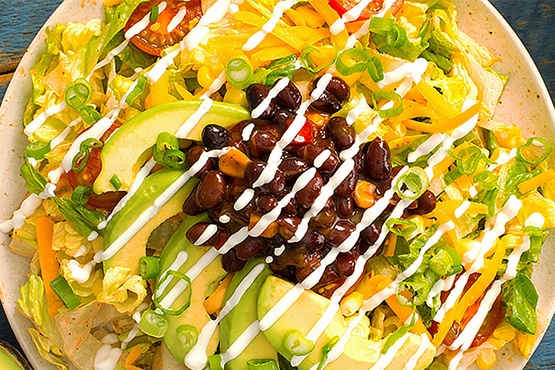 A close up of a taco salad with slices of avocado, Bush's Black Bean Fiesta and sour cream